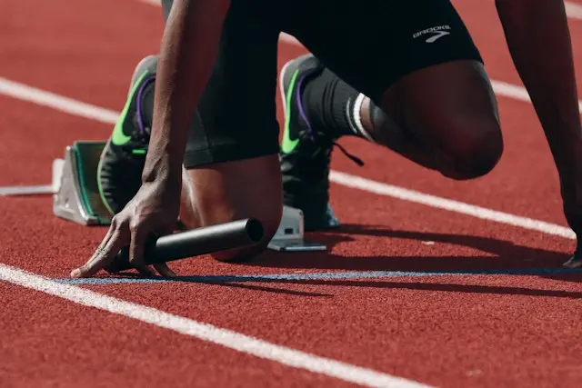 Coureur sur une piste d&rsquo;athlétisme tenant un témoin de relais